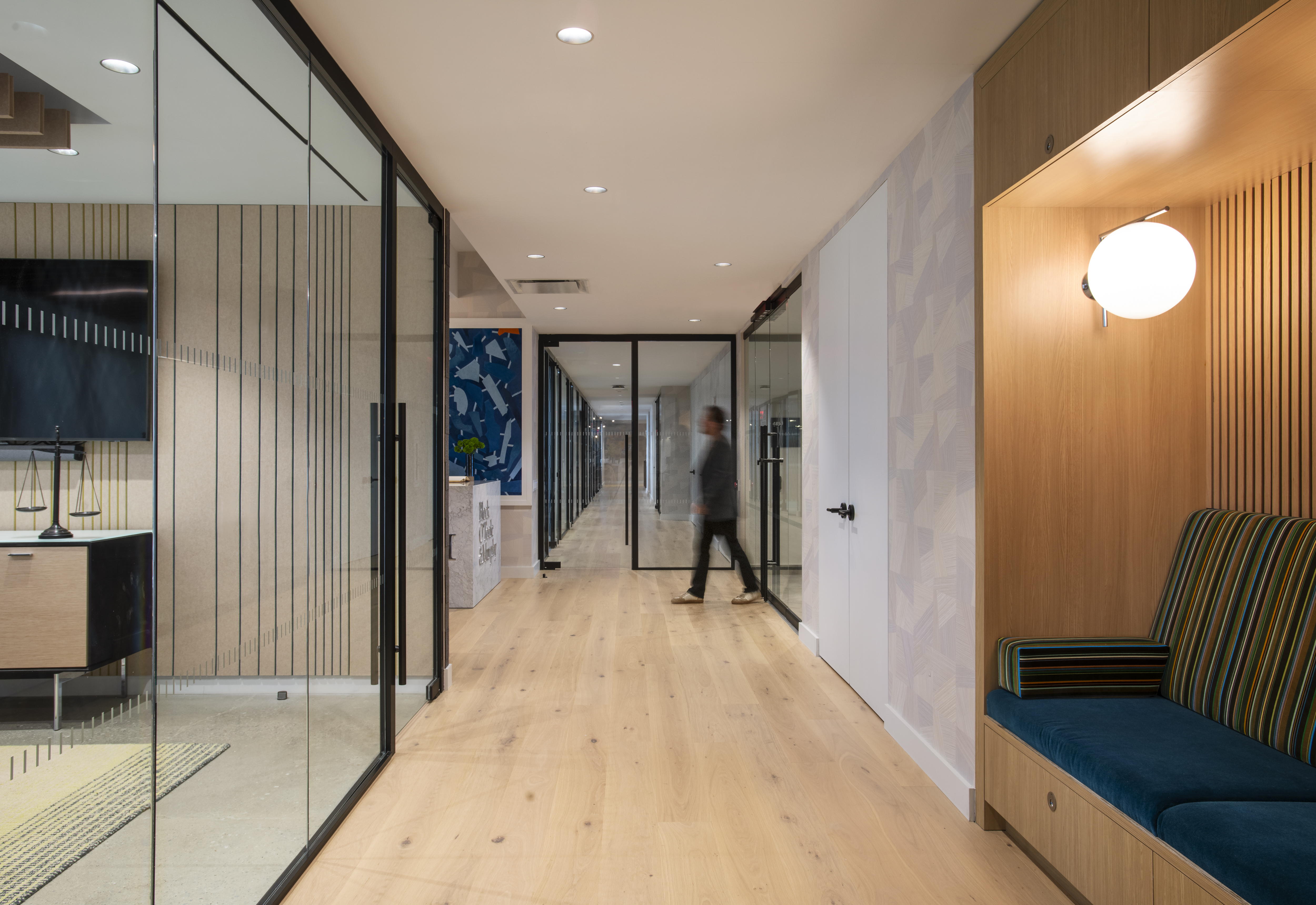 Hallway at One Penn Plaza by K.A. Murphy Interiors featuring glass office fronts, custom oak millwork, built-in seating, and contemporary workplace design.