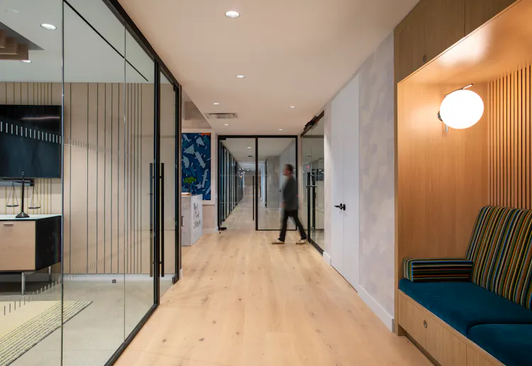 Hallway at One Penn Plaza by K.A. Murphy Interiors featuring glass office fronts, custom oak millwork, built-in seating, and contemporary workplace design.