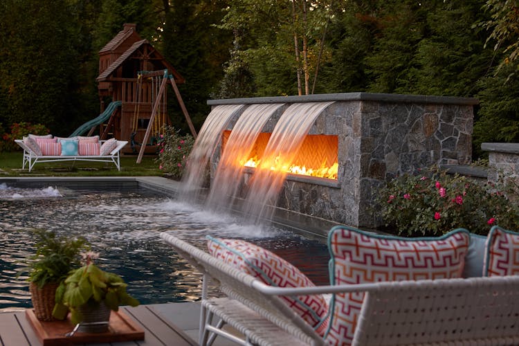 Lush backyard garden of a Long Island Colonial Revival home featuring mature landscaping and outdoor living spaces, designed by K.A. Murphy Interiors