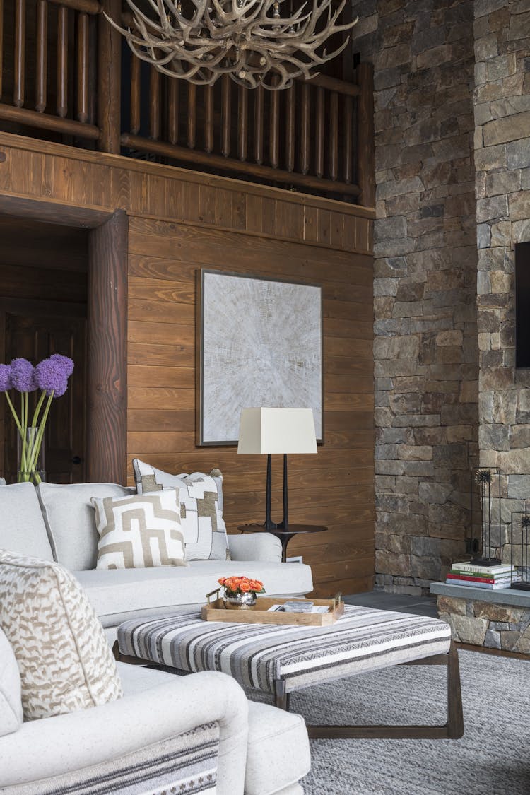 Artfully curated family room in a Hudson Valley log cabin with custom seating, layered textiles, and a statement art piece, designed by K.A. Murphy Interiors.