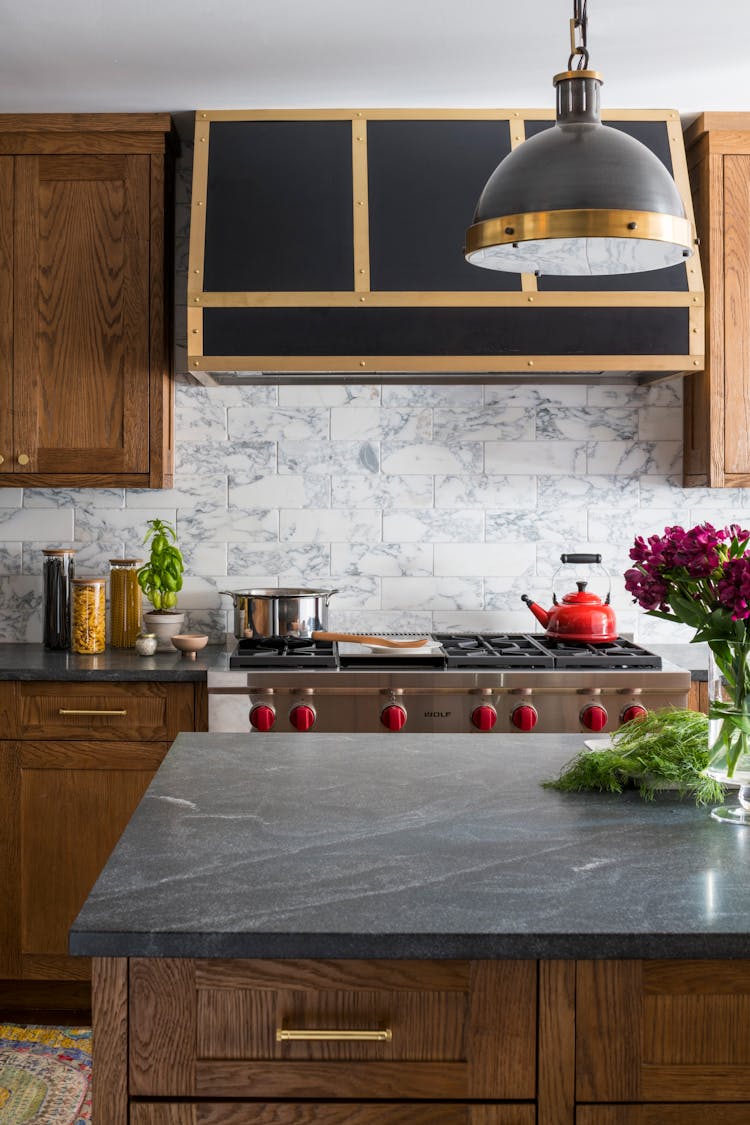 Custom kitchen stove area in a Hudson Valley log cabin with locally sourced branch millwork panels and stone backsplash, designed by K.A. Murphy Interiors