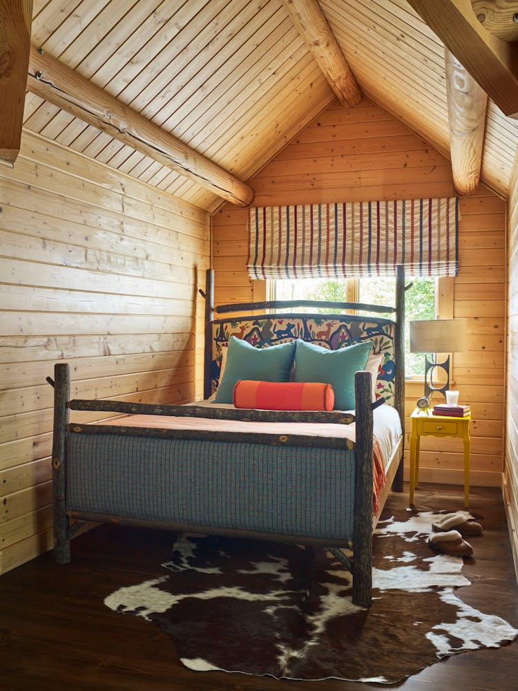 Inviting guest bedroom in a Hudson Valley log cabin with rustic furnishings and warm tones, designed by K.A. Murphy Interiors