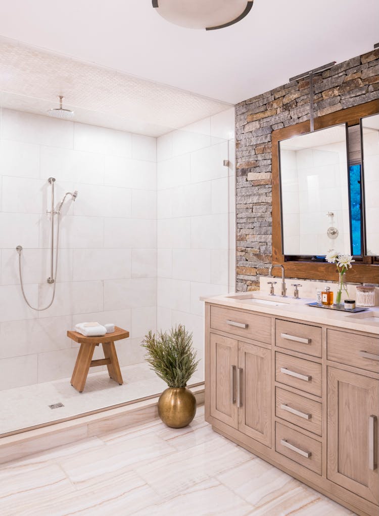 Luxurious master bathroom in a Hudson Valley log cabin featuring natural stone finishes and spa-like amenities, designed by K.A. Murphy Interiors
