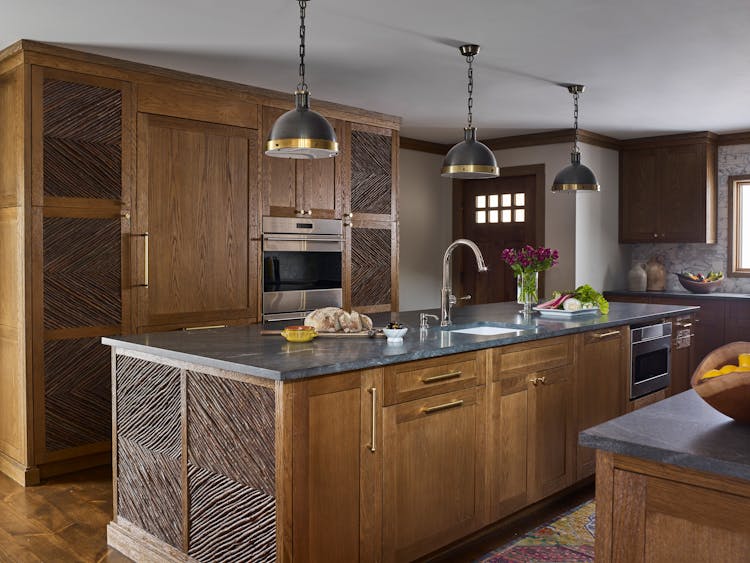 Rustic-chic kitchen in a Hudson Valley log cabin featuring locally sourced wood accents, stone countertops, and modern appliances, designed by K.A. Murphy Interiors