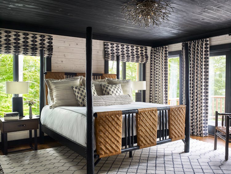 Serene master bedroom in a Hudson Valley log cabin with exposed wood beams, natural textiles, and a tranquil ambiance, designed by K.A. Murphy Interiors