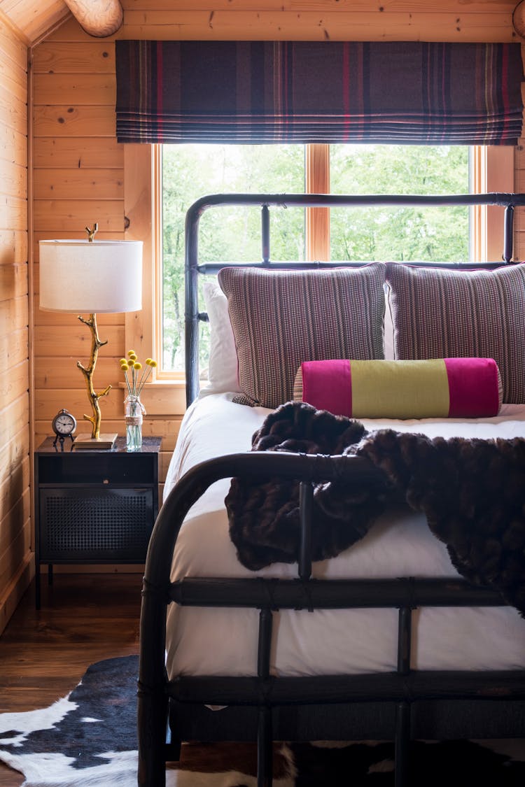Inviting guest bedroom in a Hudson Valley log cabin with rustic furnishings and warm tones, designed by K.A. Murphy Interiors