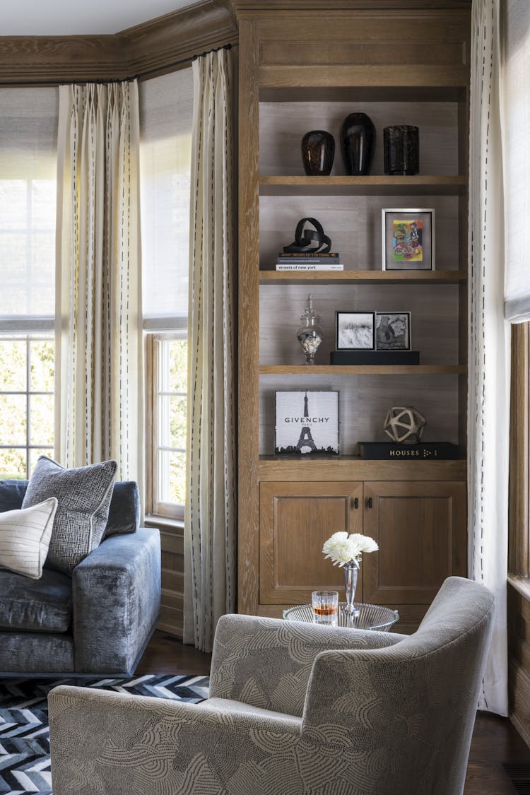 Custom wood-paneled built-in shelves with husk wallpaper in a New York study, designed by K.A. Murphy Interiors