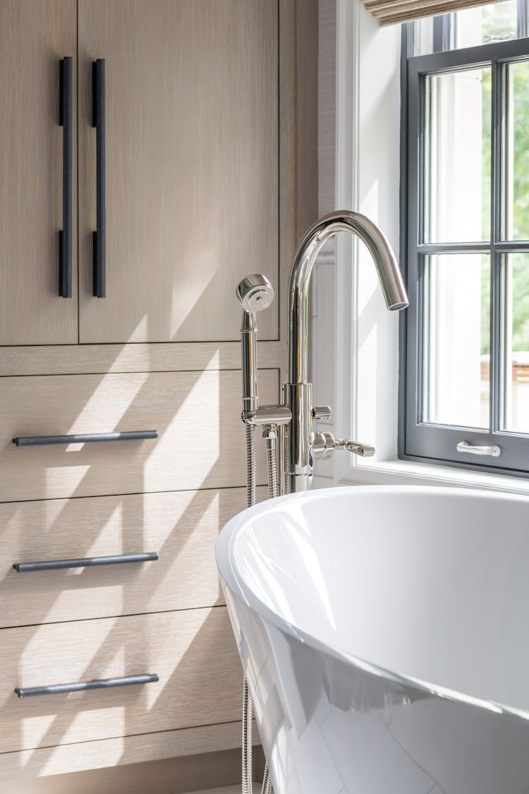 Detailed view of bathtub hardware and surrounding surfaces in a Long Island spa bathroom, designed by K.A. Murphy Interiors