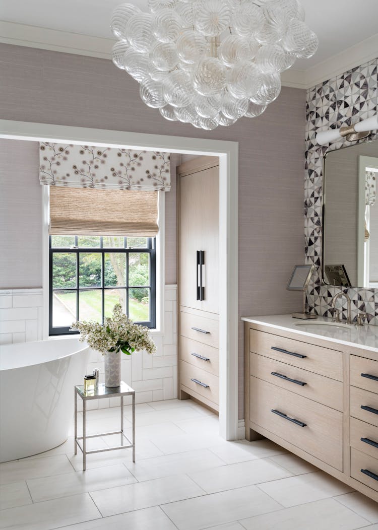 Freestanding bathtub paired with a custom vanity in a Long Island spa-inspired bathroom, designed by K.A. Murphy Interiors
