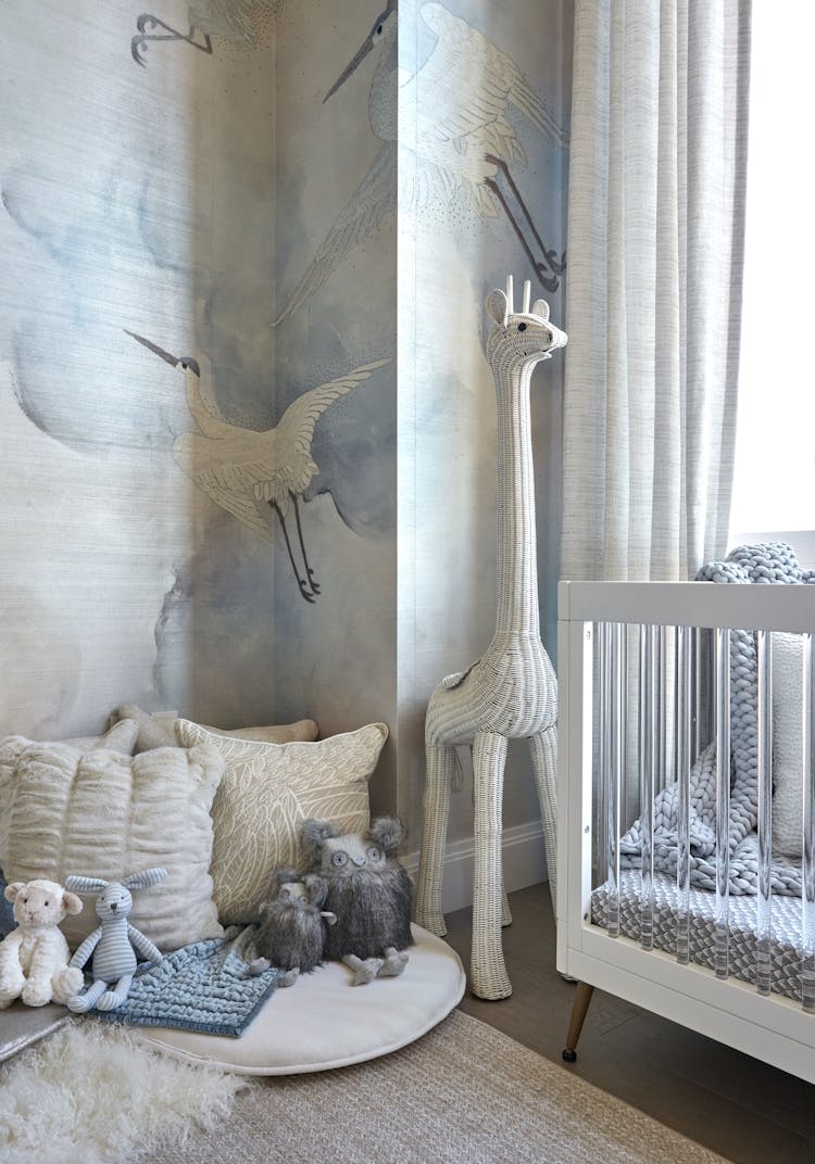 Whimsical crane mural above a white crib in a Manhattan nursery, designed by K.A. Murphy Interiors.
