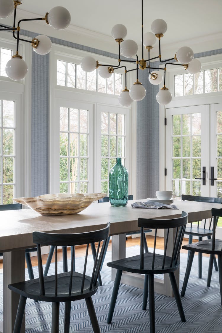 Elegant dining table seating in a Long Island family home, featuring bold industrial-inspired lighting, designed by K.A. Murphy Interiors