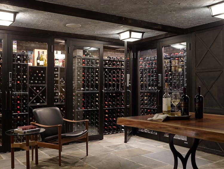 Custom wine cellar in a Long Island Colonial Revival home featuring built-in racks, ambient lighting, and a sophisticated design, designed by K.A. Murphy Interiors