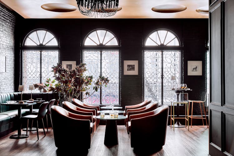 Elegant gentleman’s lounge in Lower Manhattan with black brick walls, green velvet seating, and sculptural furniture, designed by K.A. Murphy Interiors