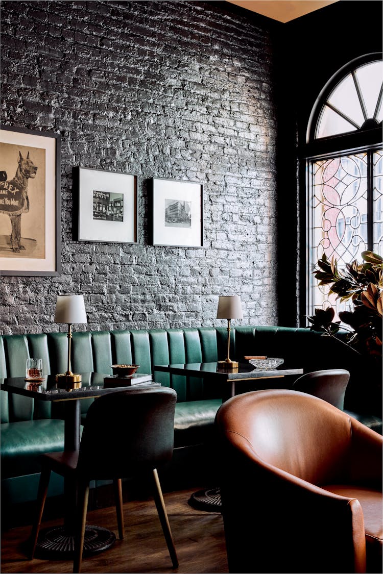 Intimate booth seating with green velvet upholstery and brass accents in a Lower Manhattan gentleman’s lounge, designed by K.A. Murphy Interiors.