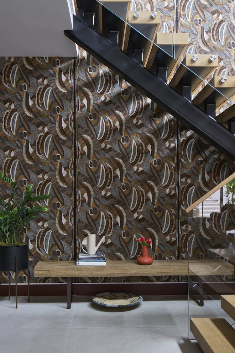 Staircase wrapped in textile-inspired wallpaper in the foyer of a Hamptons show house, designed by K.A. Murphy Interiors