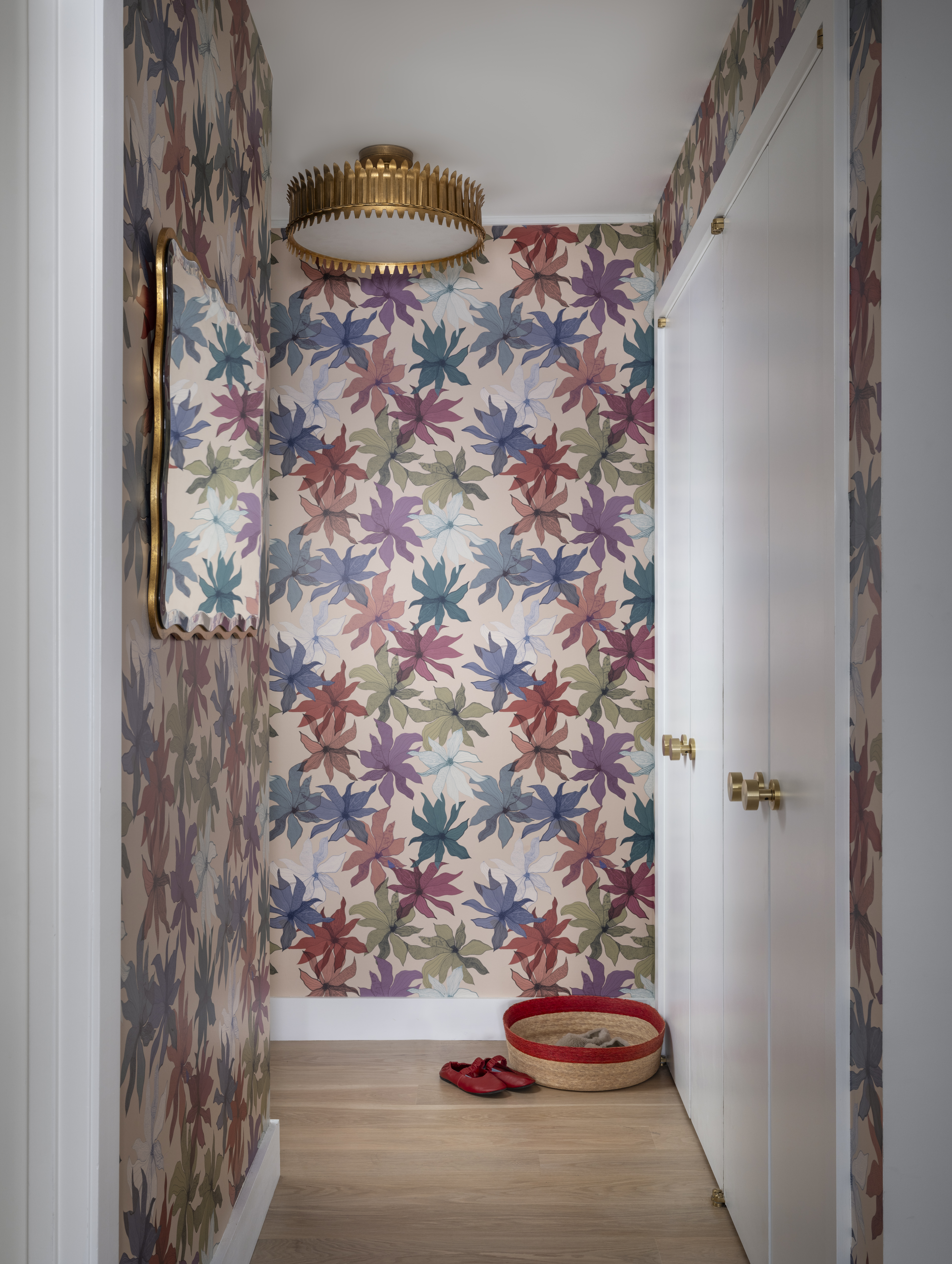 Greenwich Village apartment foyer featuring colorful floral wallpaper, a sculptural brass ceiling light, and custom millwork by K.A. Murphy Interiors.