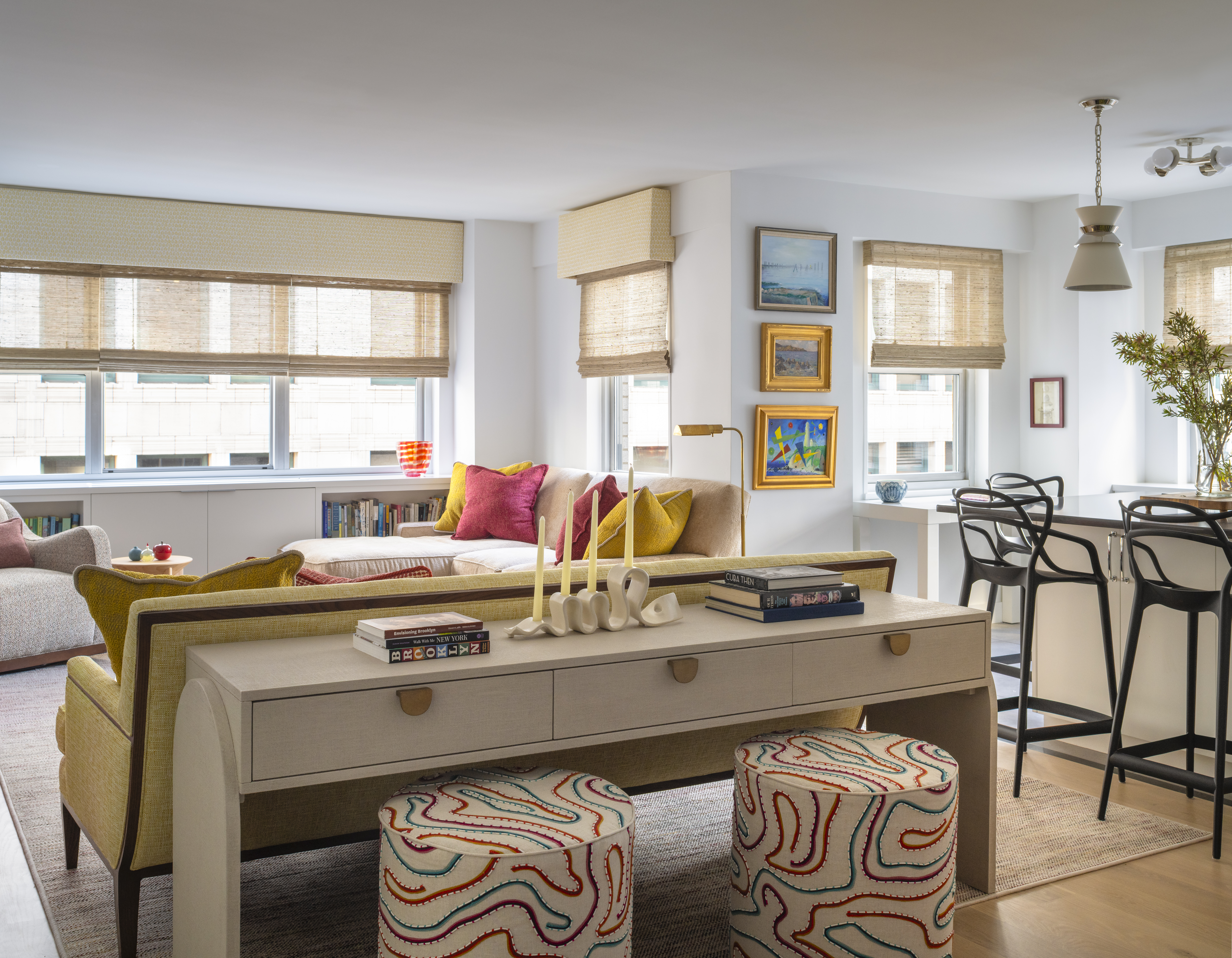 Colorful Greenwich Village living and dining area featuring a yellow sofa, patterned ottomans, layered artwork, and custom furnishings by K.A. Murphy Interiors.