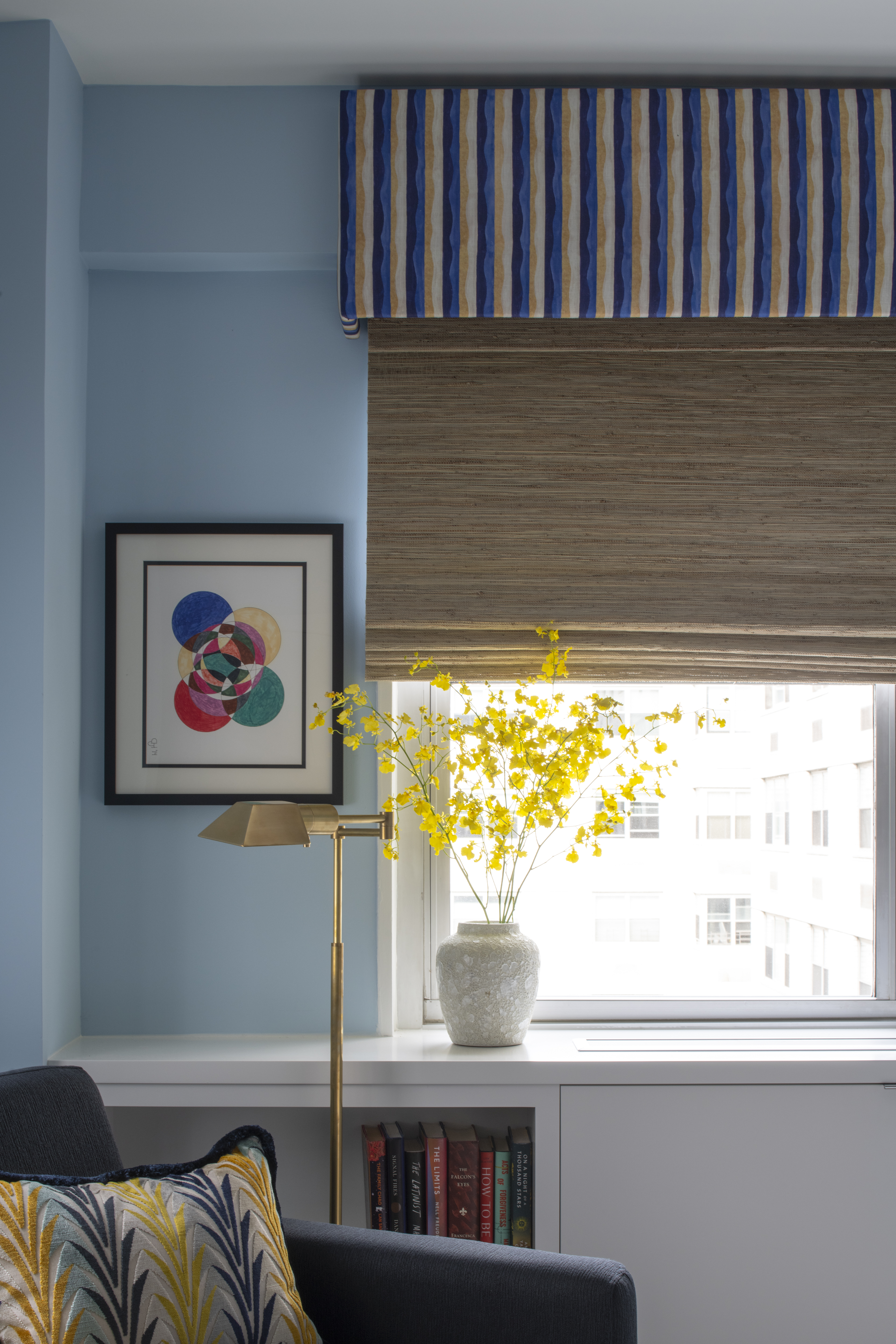 Detail of guest bedroom window featuring custom striped valance, woven shade, and brass reading lamp by K.A. Murphy Interiors.