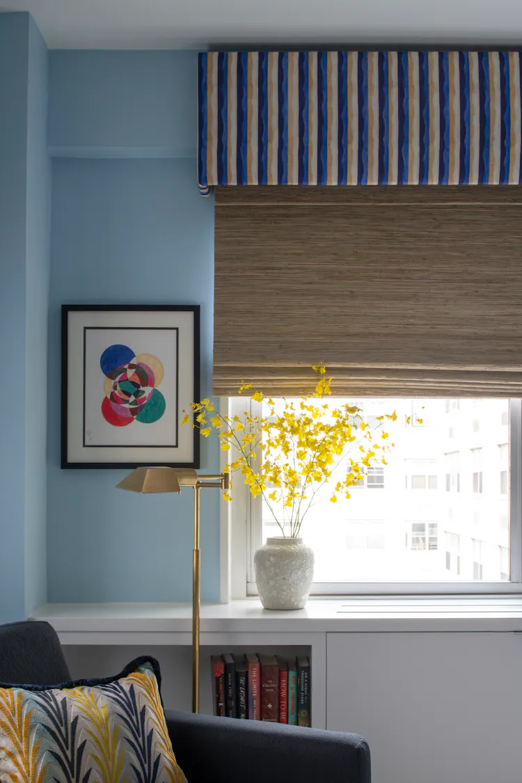 Detail of guest bedroom window featuring custom striped valance, woven shade, and brass reading lamp by K.A. Murphy Interiors.