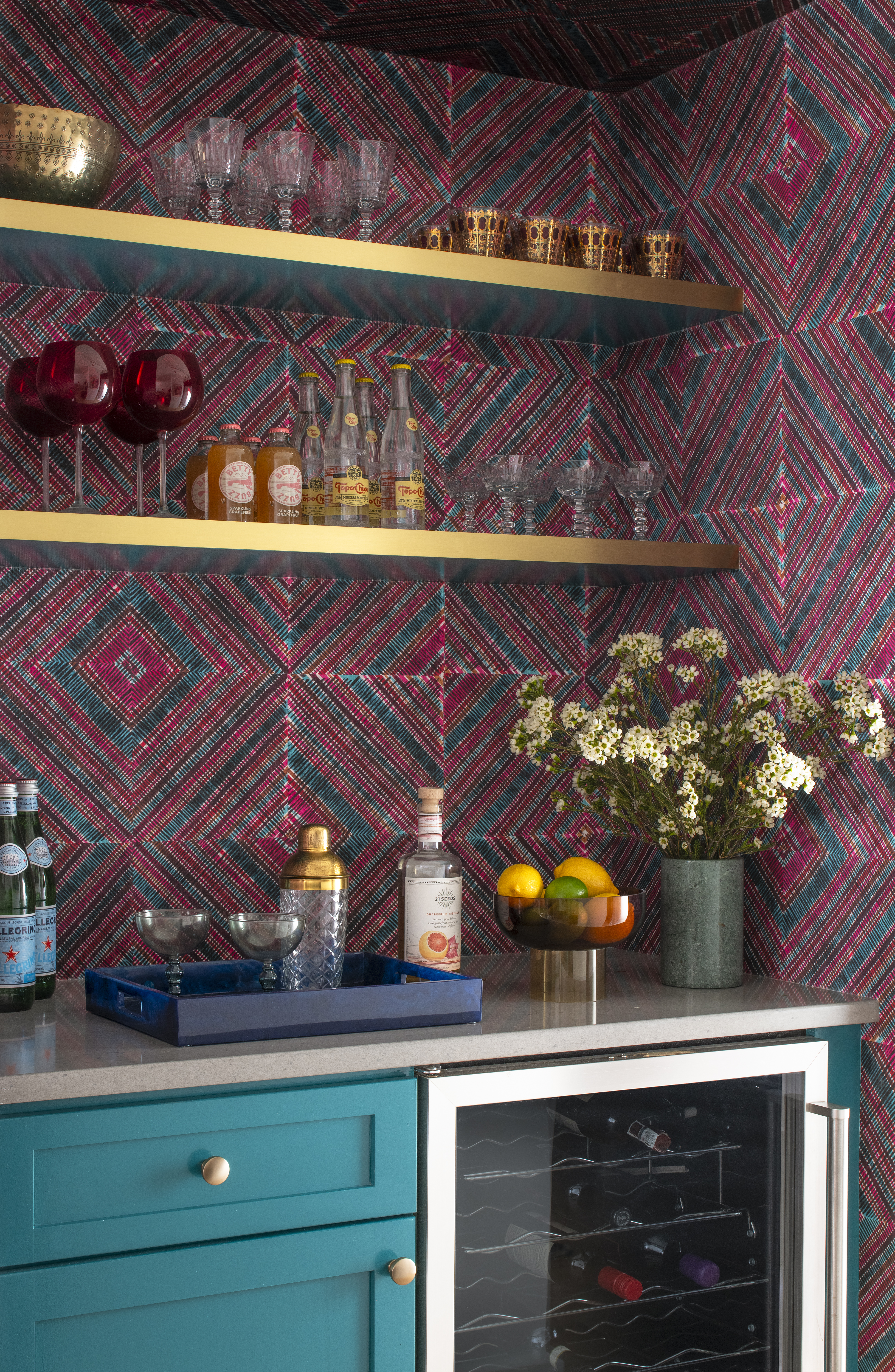 Bar nook with graphic wallcovering, brass shelving, and curated glassware in a Greenwich Village apartment by K.A. Murphy Interiors.