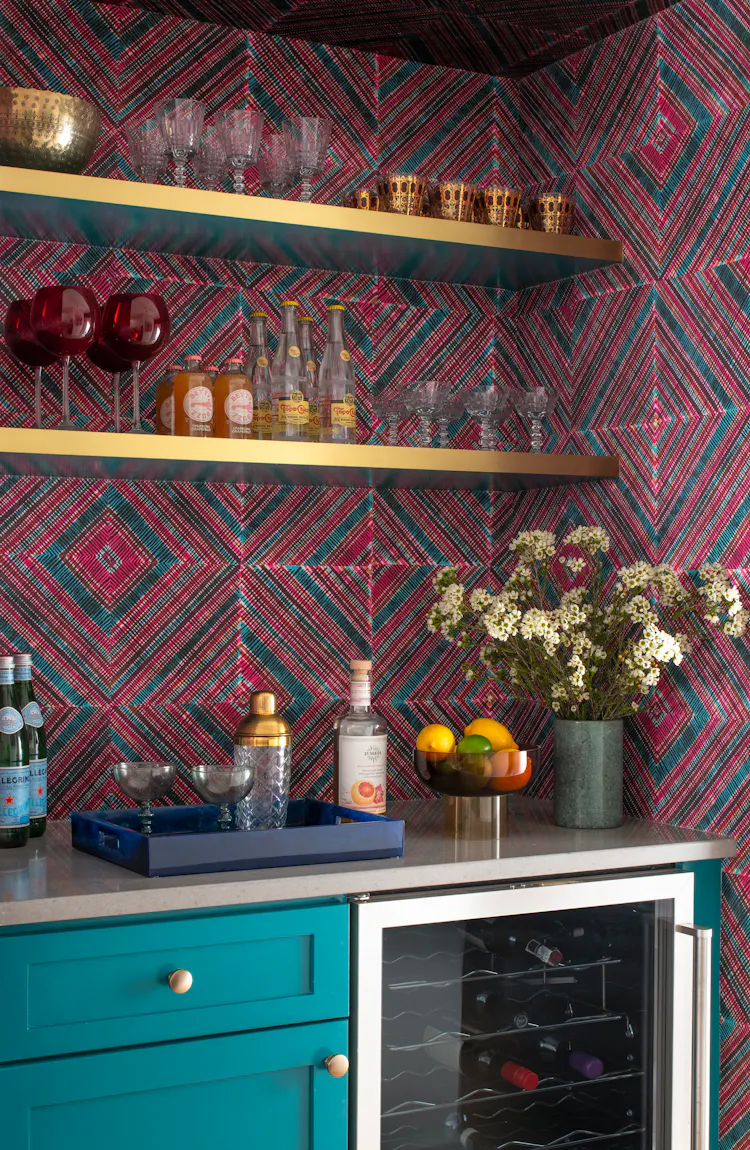 Bar nook with graphic wallcovering, brass shelving, and curated glassware in a Greenwich Village apartment by K.A. Murphy Interiors.