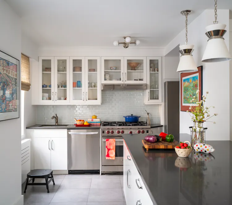 Bright Greenwich Village kitchen with white cabinetry, glass-front uppers, and a charcoal stone island by K.A. Murphy Interiors.