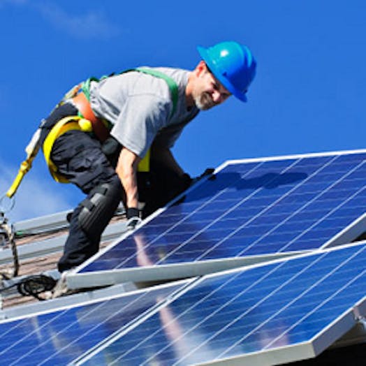 A man standing on a roof installing solar panels