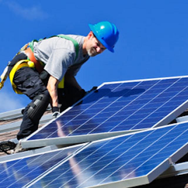 A man standing on a roof installing solar panels
