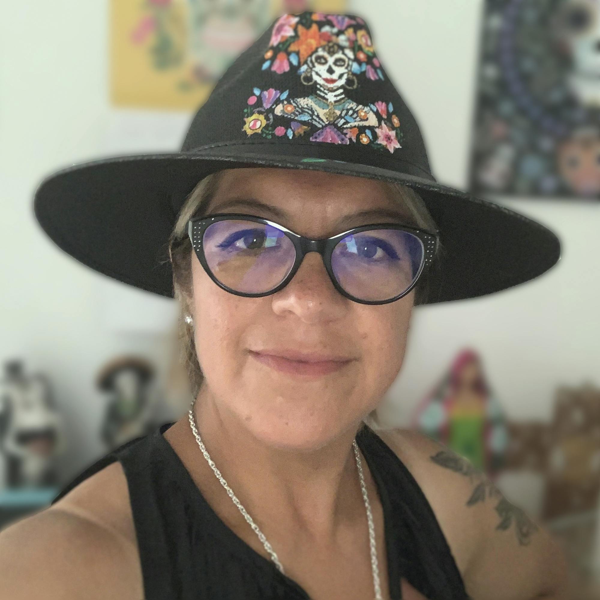 Ana Hernandez, in glasses and colorful hat, smiling
