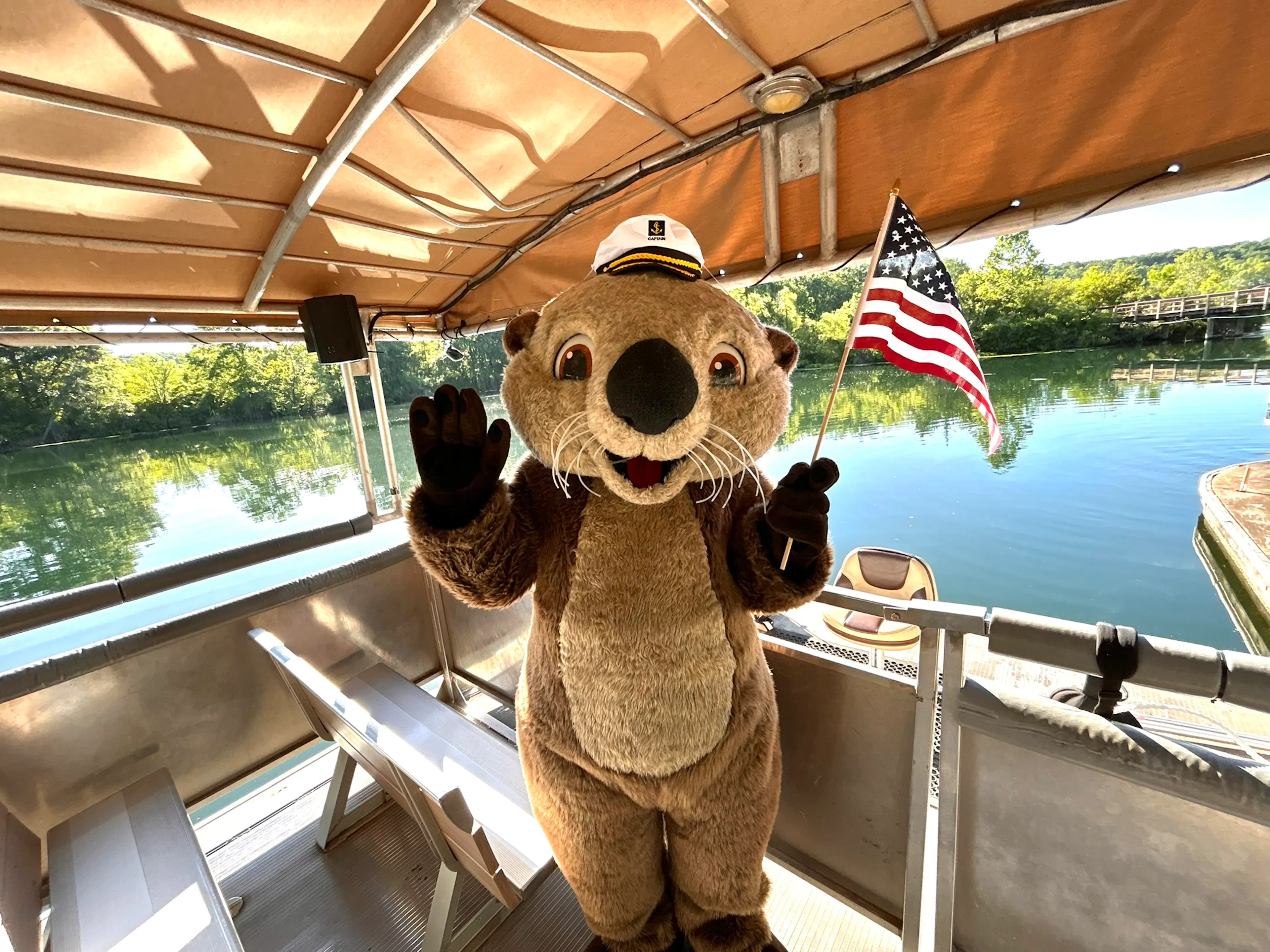 Ollie the otter mascot holding american flag on a boat
