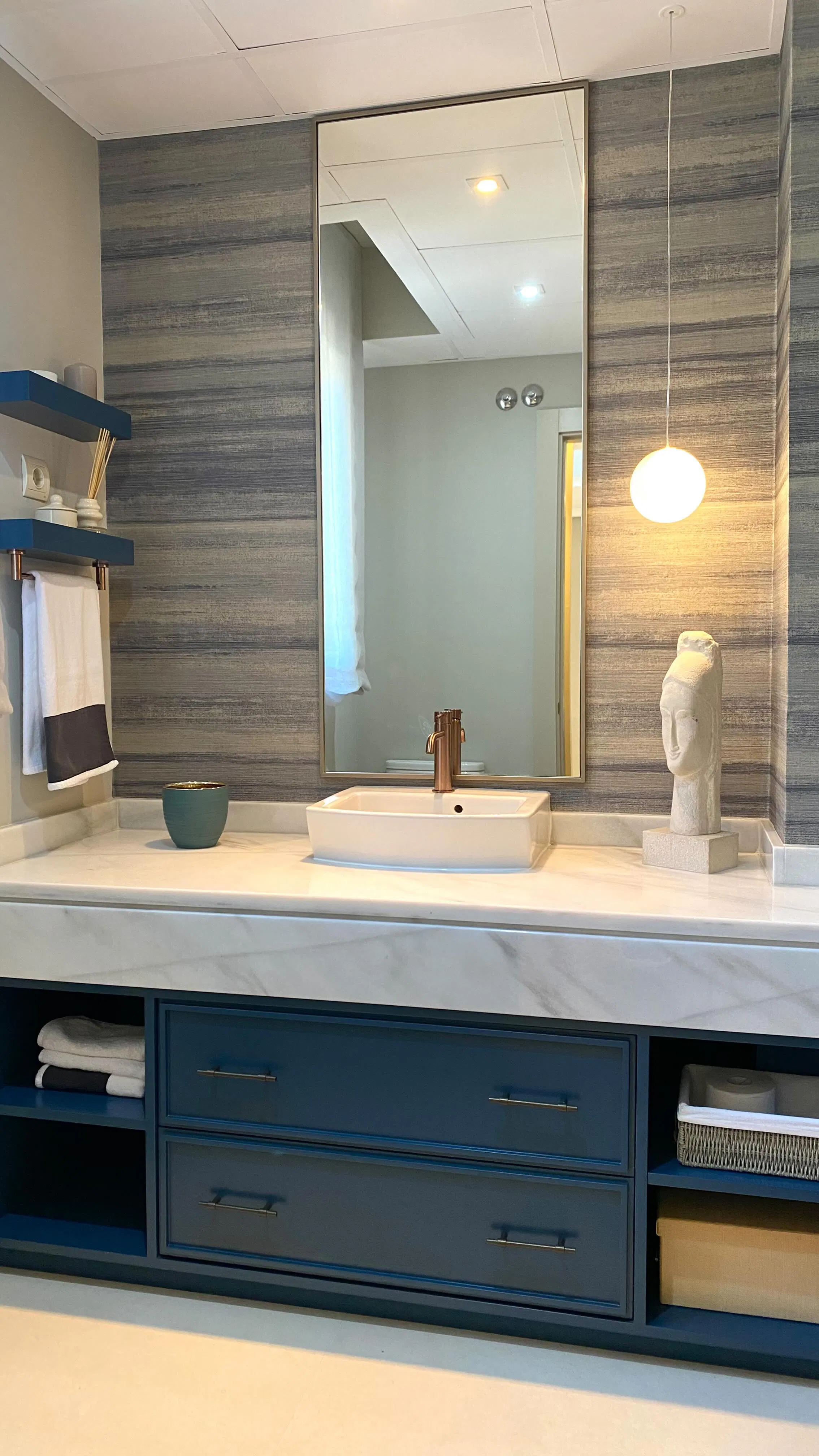 Aseo con mueble azul a medida, mármol e iluminación suspendida