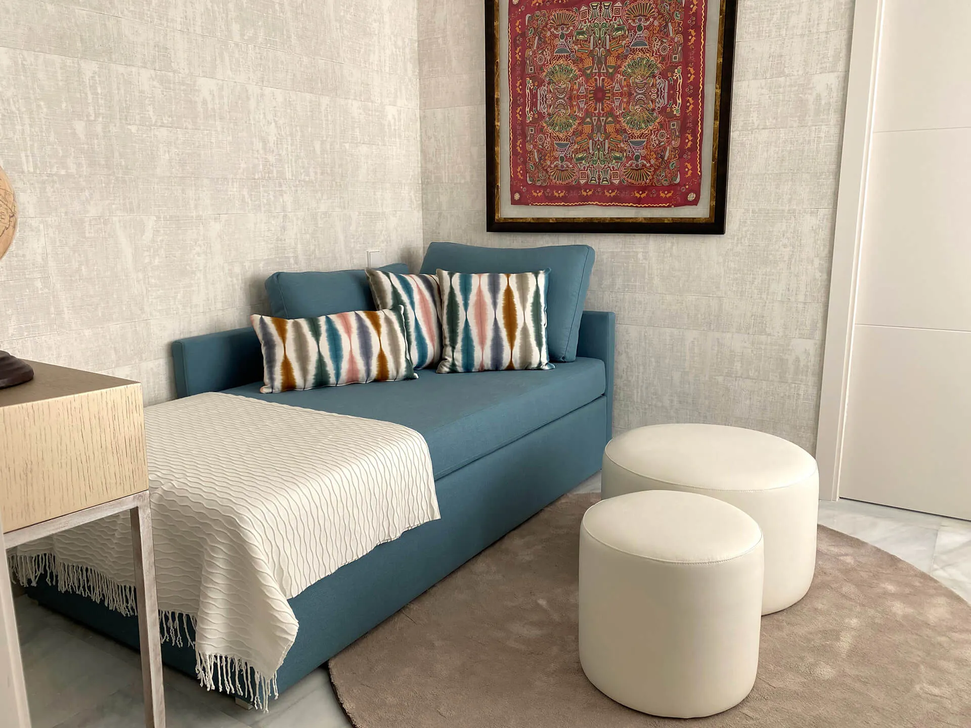 Detalle sofá, pufs, papel pintado y tapiz exclusivo del proyecto de decoración en Marbella
