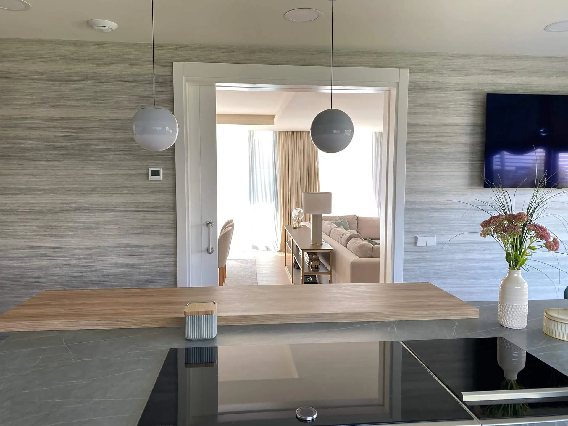Perspectiva desde la cocina de la entrada al salón con puerta corredera del proyecto de decoración en Majadahonda