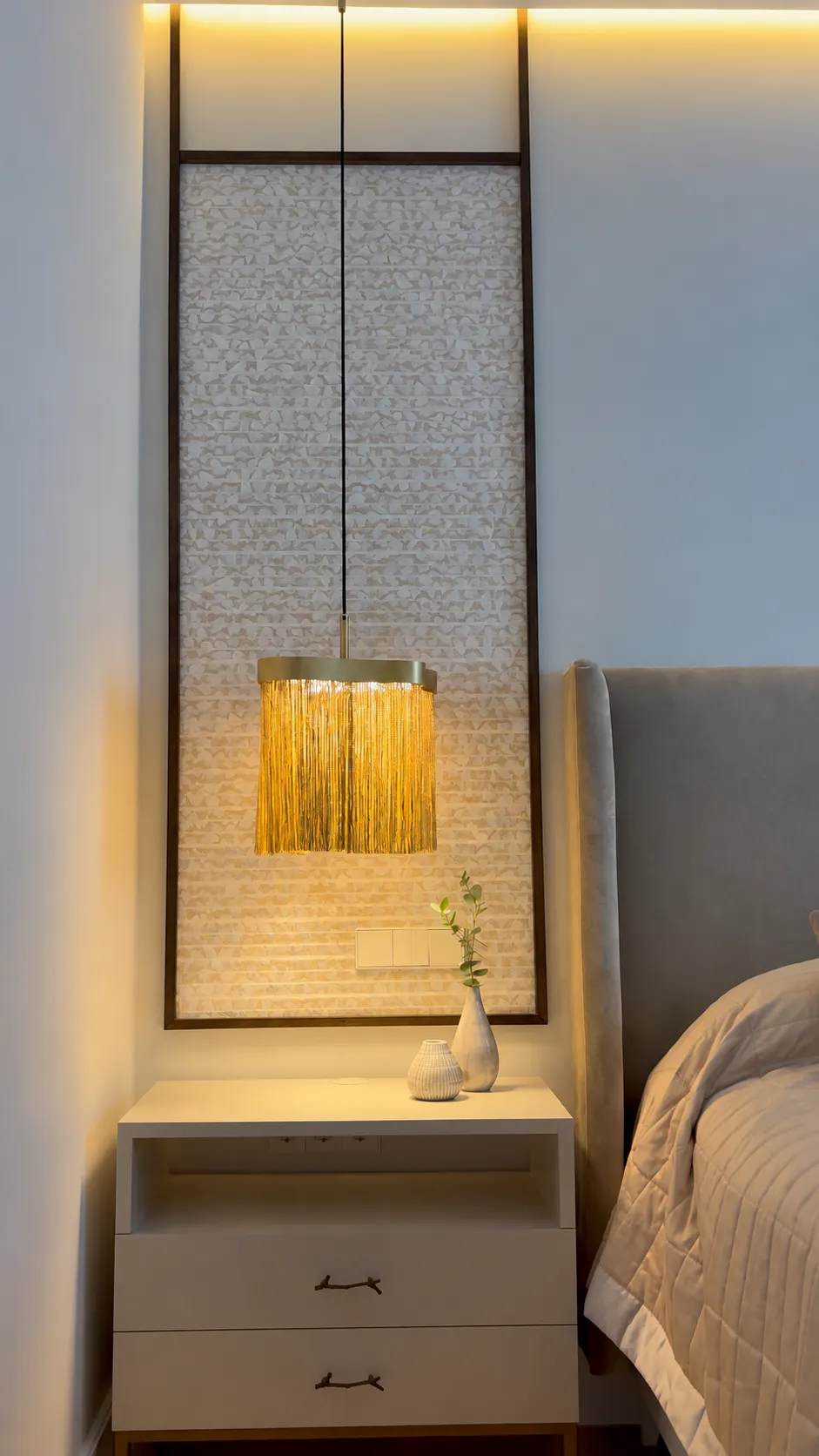 Dormitorio con panel textil, mobiliario a medida e iluminación cálida