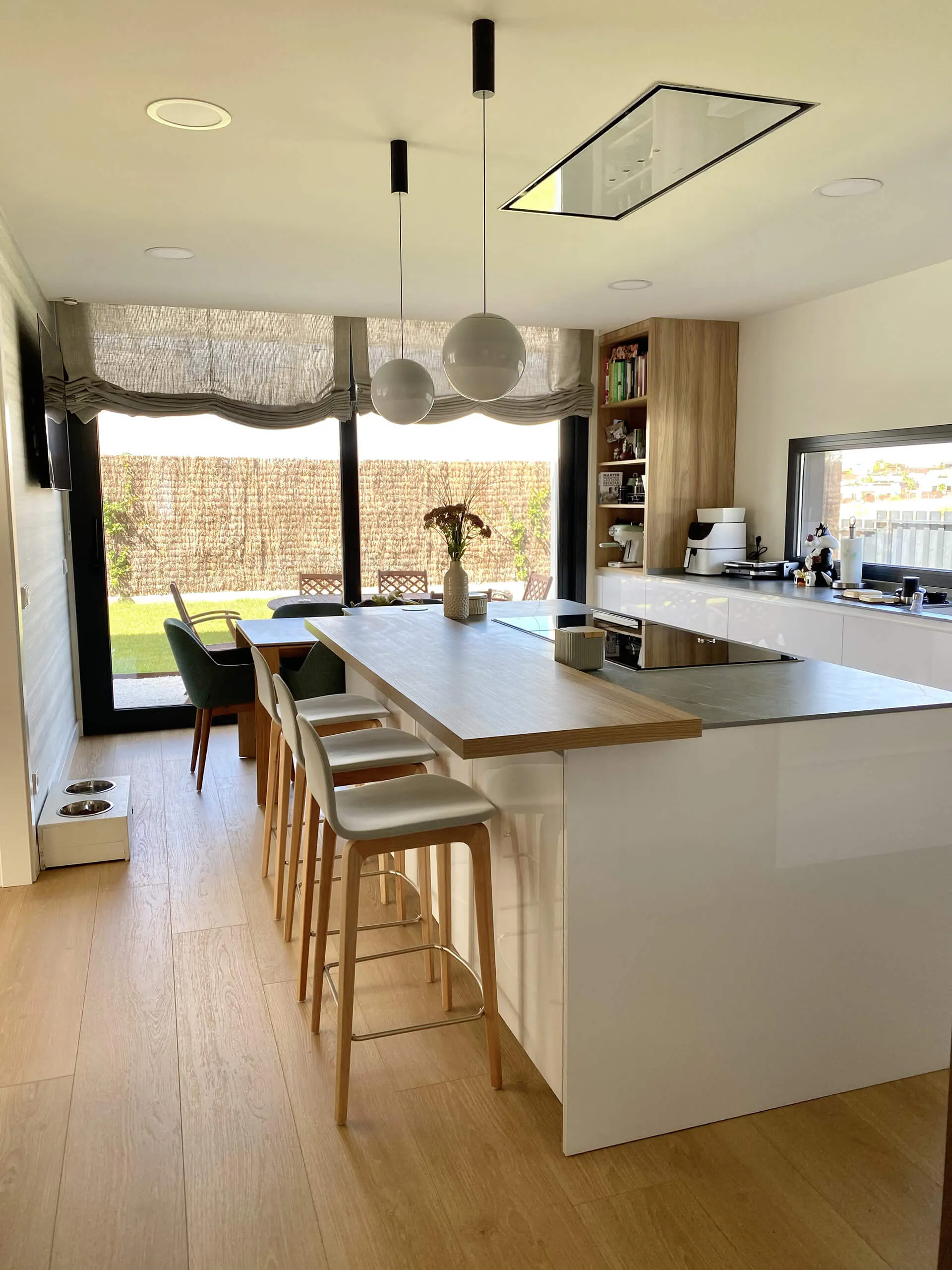 Isla de cocina con sillería, inducción y campana integrada en techo del proyecto de decoración en Majadahonda