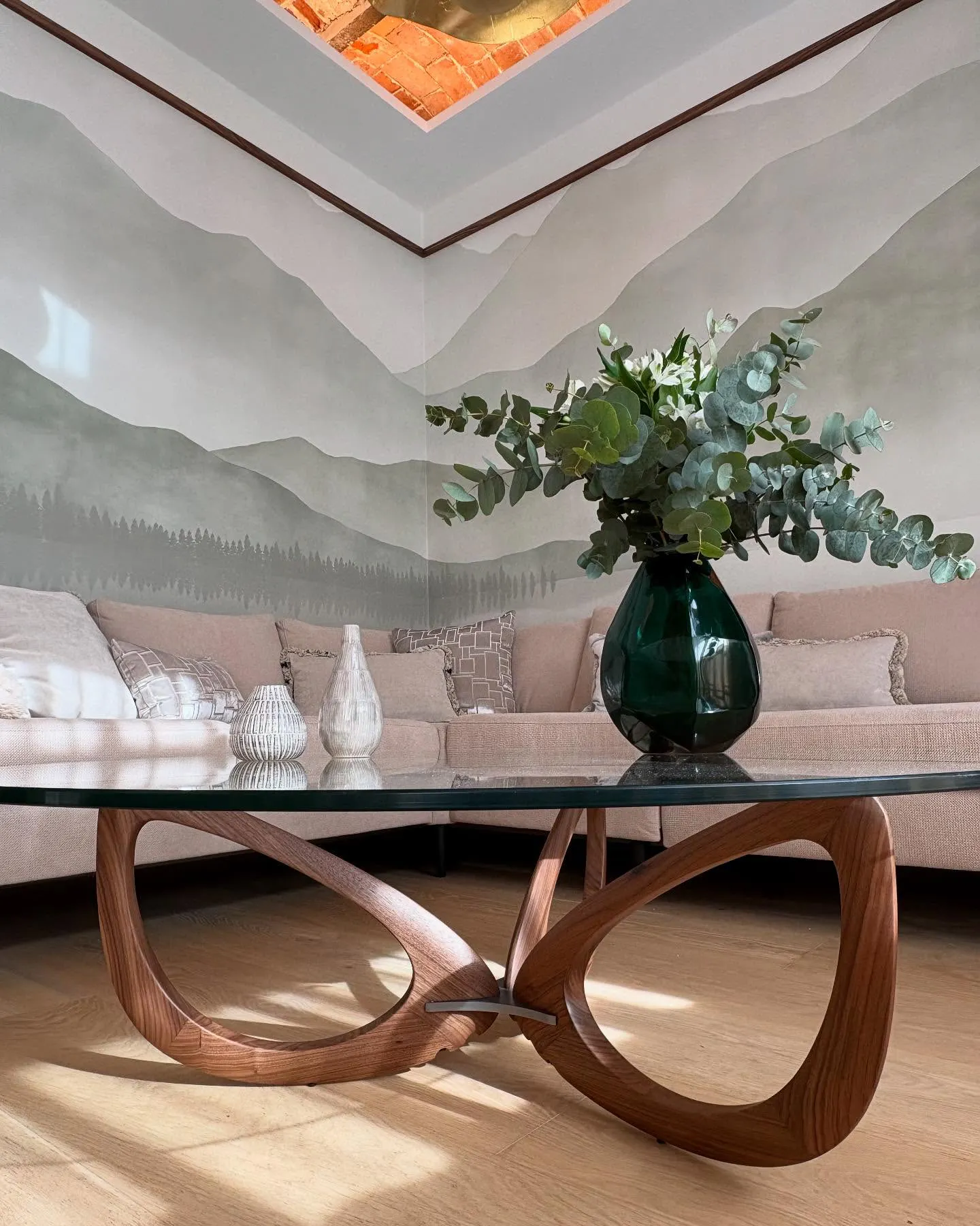 Detalle de salón con mural panorámico y mesa escultórica de madera