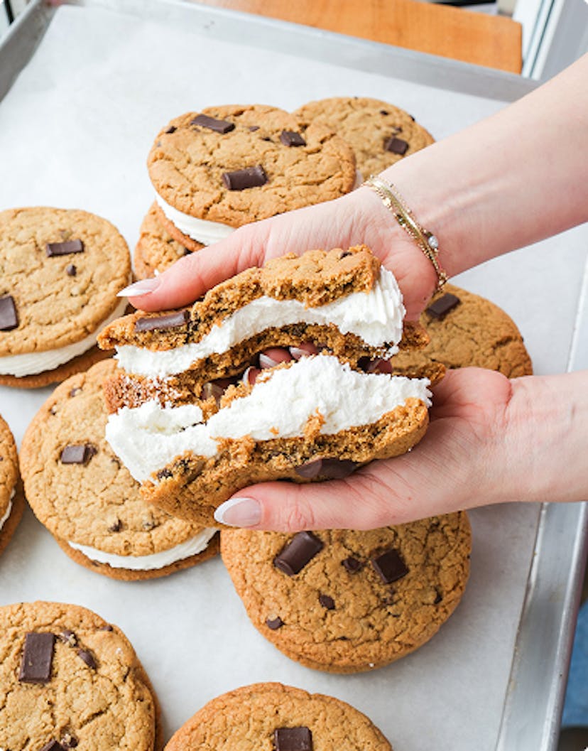 chocolate chip cookie sandwich broken in half to show the frosting in the middle, more cookies in the background