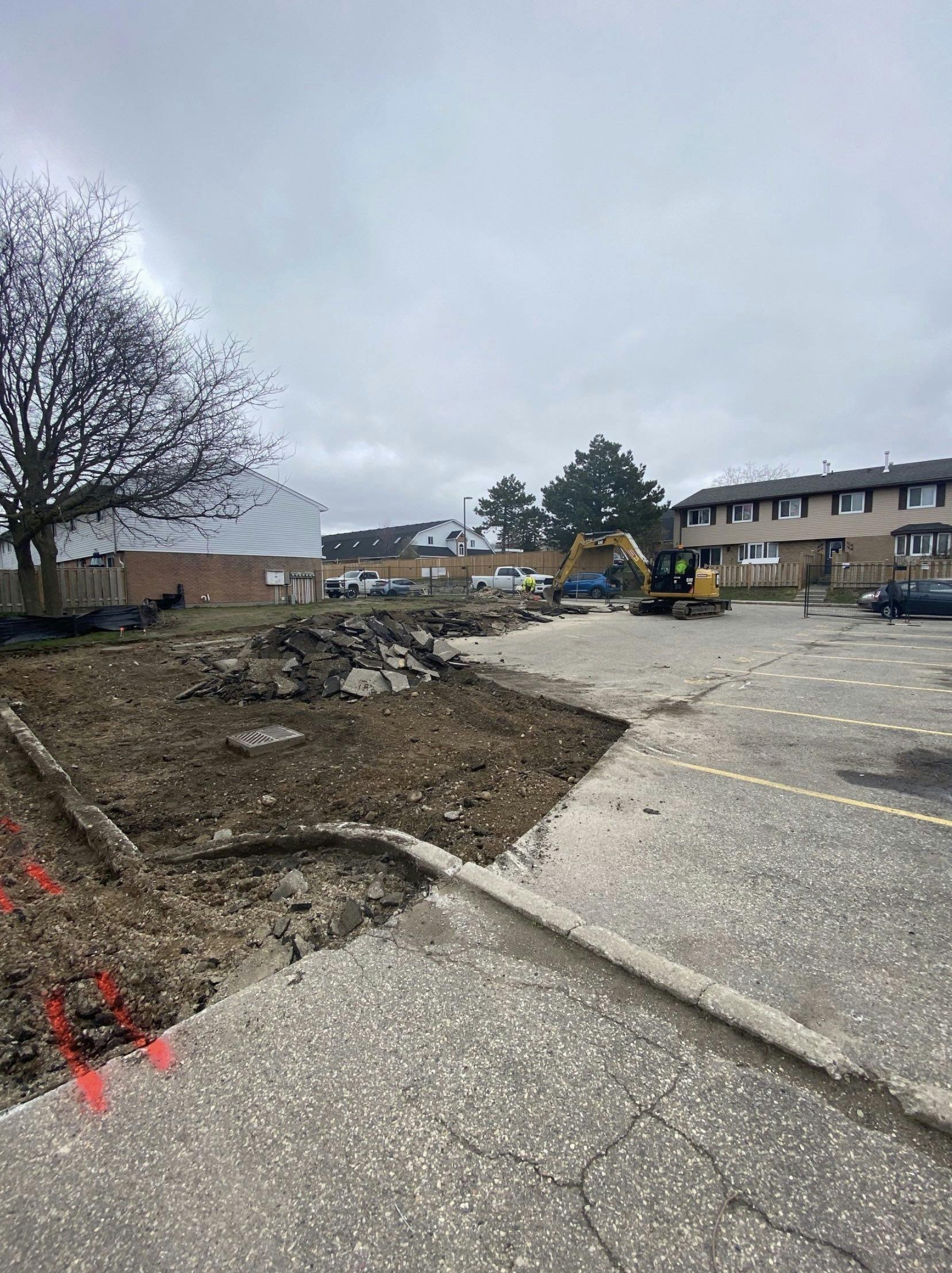 Excavator removes old cracked pavement to prepare for a new parking lot. 