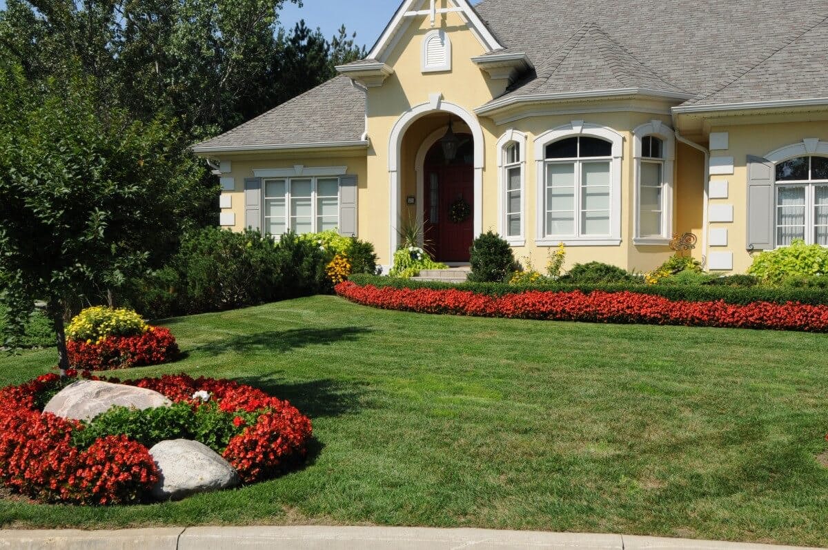 Maintained freshly cut lawn in front of a large beige house