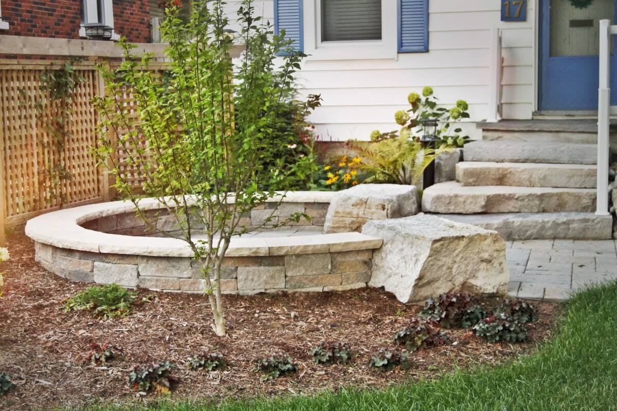 Rear door of home leads to interlocking stone stairs and pathway. Path leads to a circular, one foot stone wall with bench top. This area provides a sitting area for fire pit.  