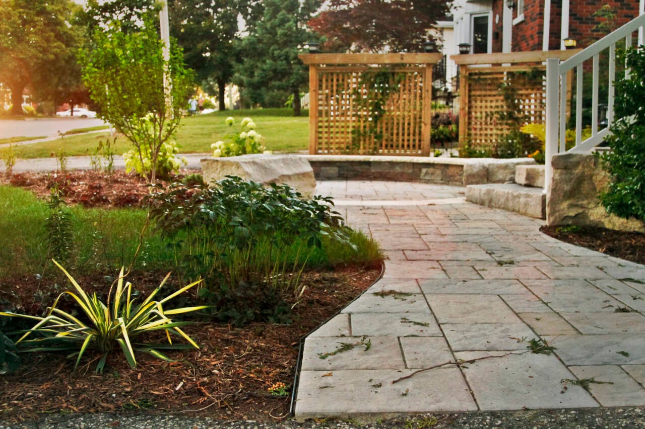 Beautiful interlock pathway extends across the front of house. Natural stone steps lead from the pathway up to the doorway. Pathway is cut into garden area providing beautifully sculptured edge to the flanking garden. 