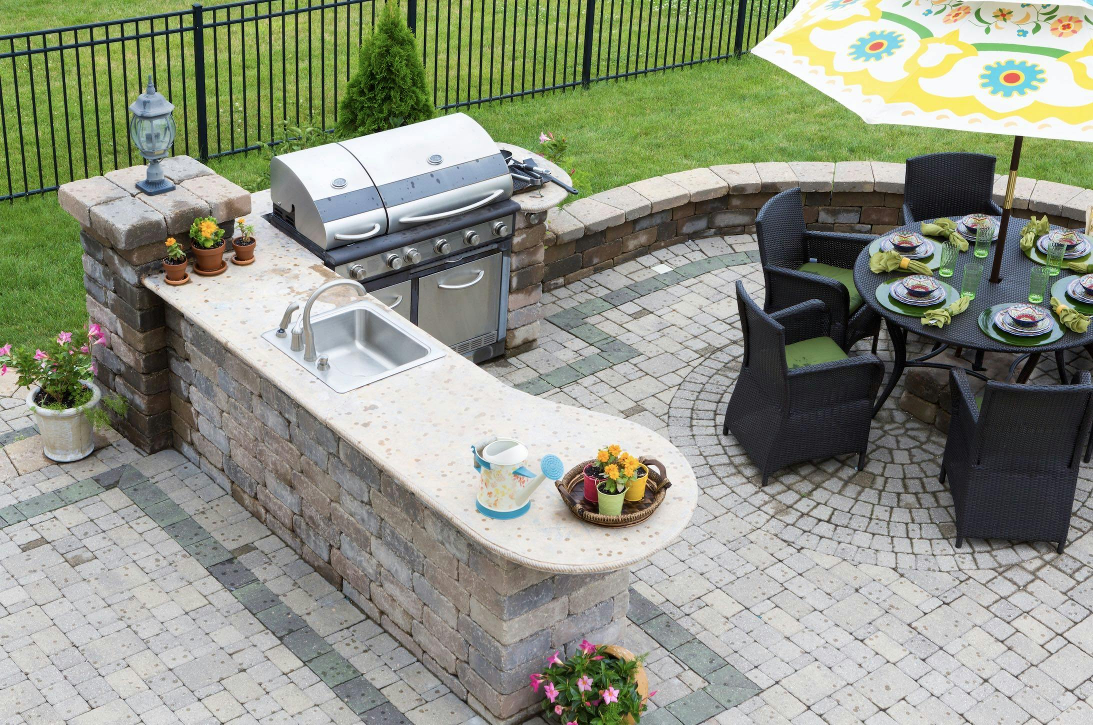 Outdoor kitchen area with BBQ and patio table with yellow umbrella