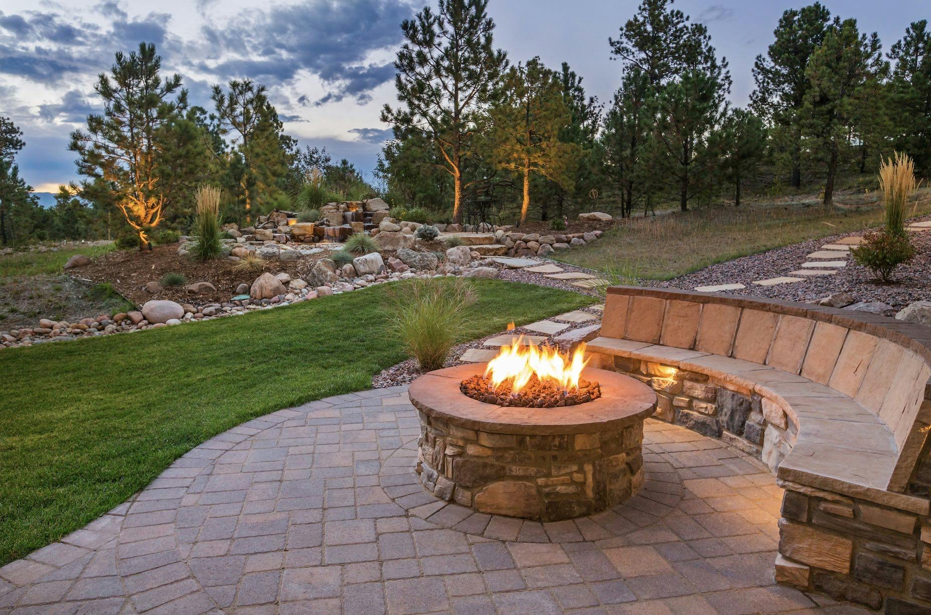 An outdoor firepit with on a patio with stone seating