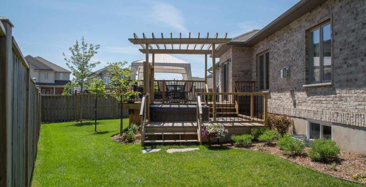 Backyard deck with medal spindle railing and built in pergola covering.