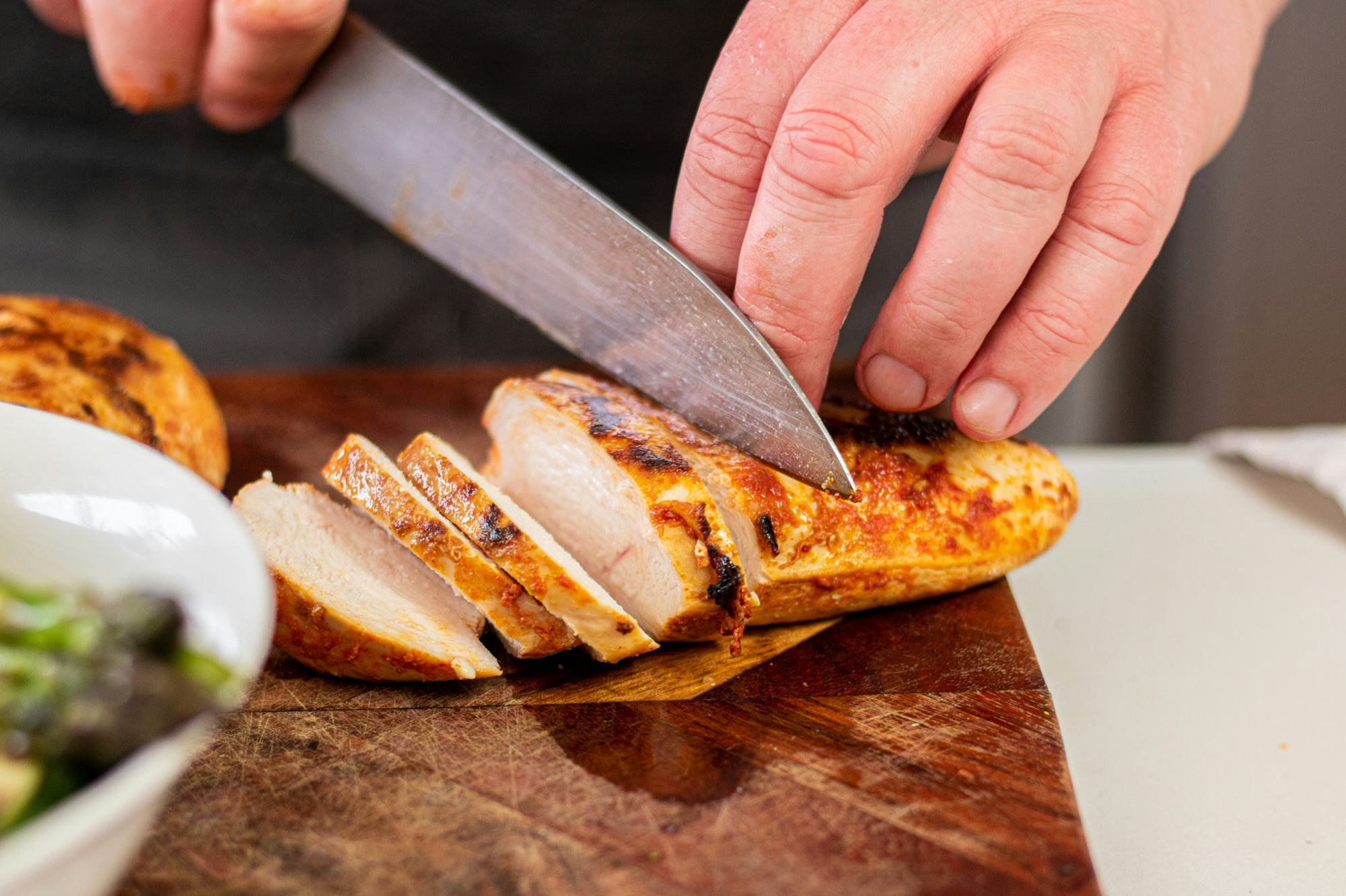 person slicing chicken with knife