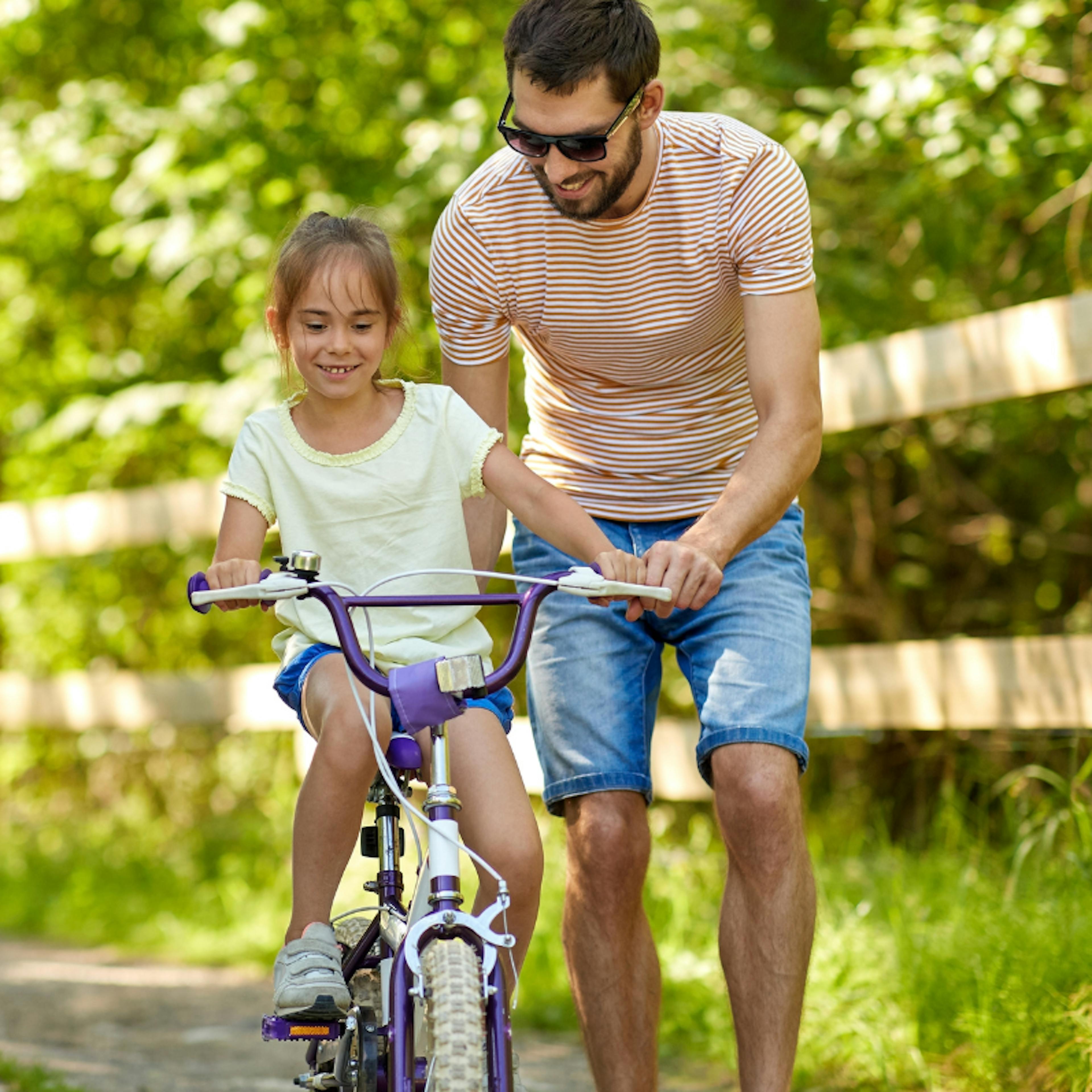 Girl learning to ride bike with dad
