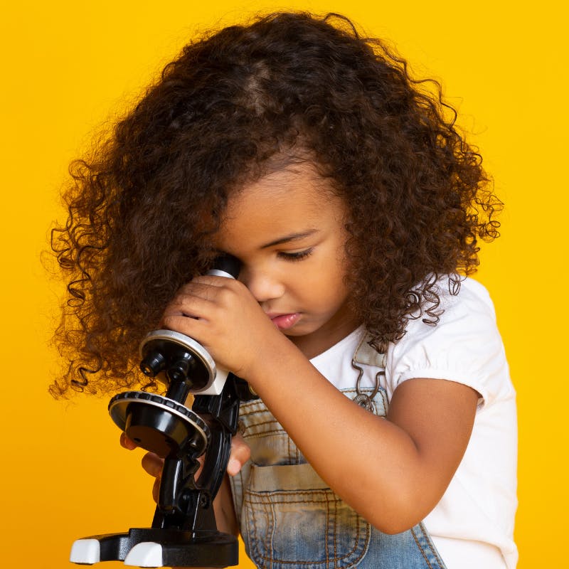 Little girl looking through microscope