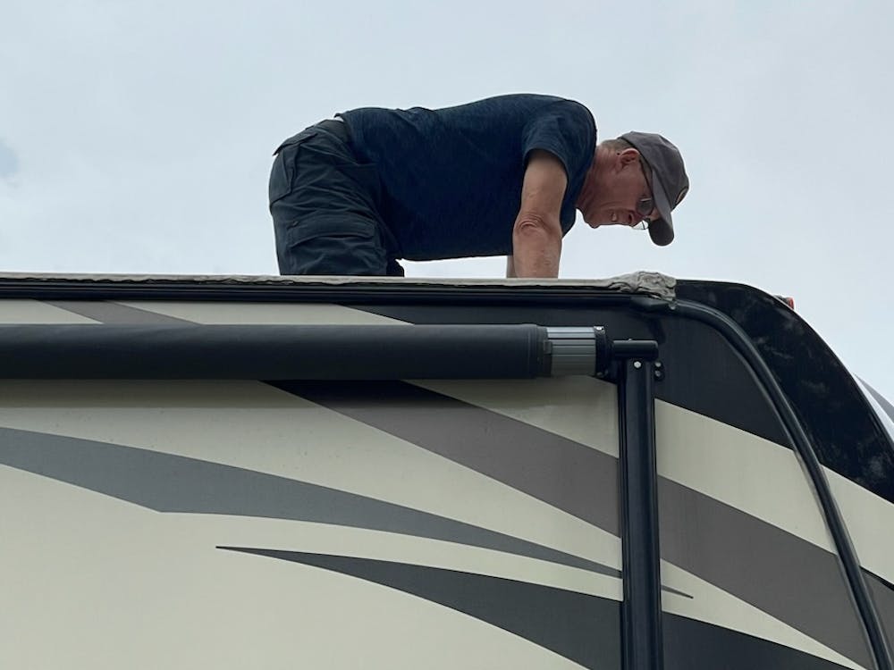 Man on RV roof inspecting seals