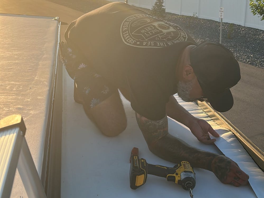Man on RV roof replacing slide out edging and seals