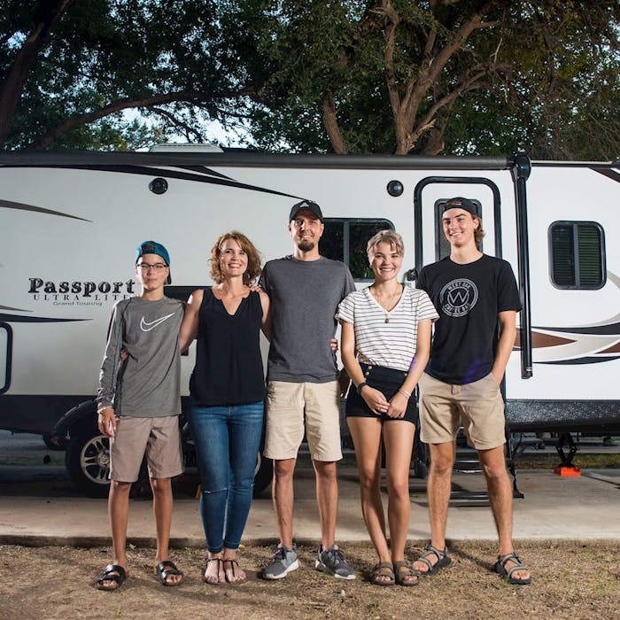 Family standing in front of thier Keystone Passport RV travel trailer. 